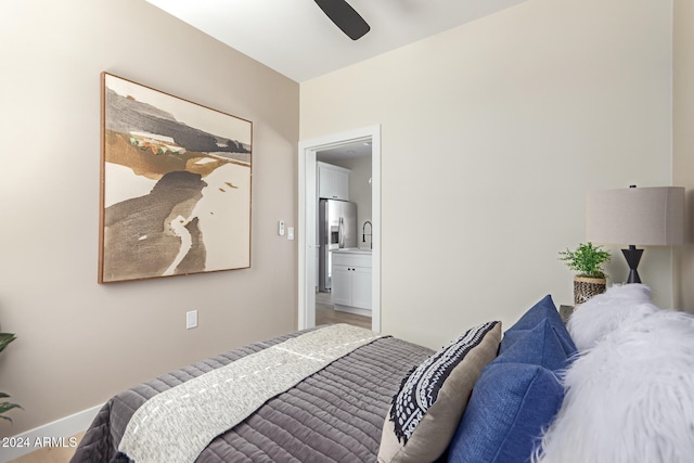 bedroom with ceiling fan, hardwood / wood-style flooring, stainless steel fridge, and ensuite bath