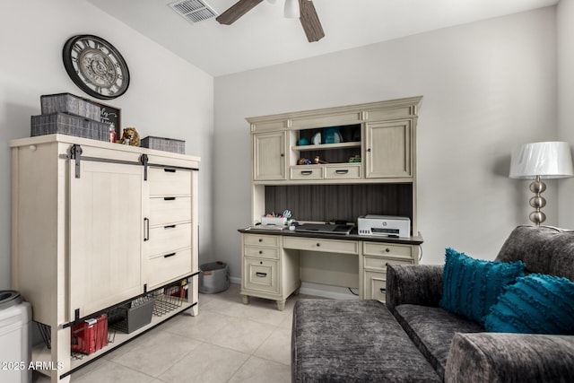 office space featuring ceiling fan, light tile patterned floors, built in desk, and a barn door