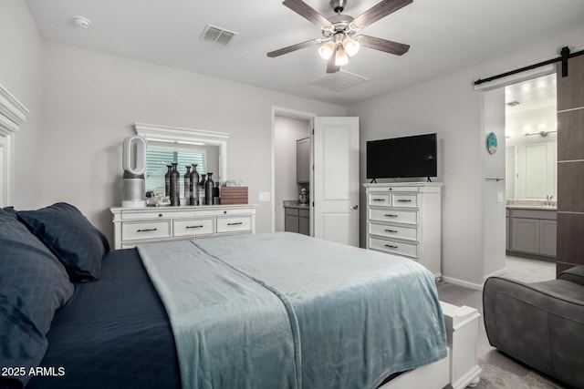 bedroom with a barn door, light carpet, baseboards, a sink, and connected bathroom