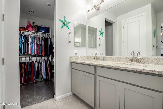 full bathroom with a walk in closet, tile patterned flooring, double vanity, and baseboards