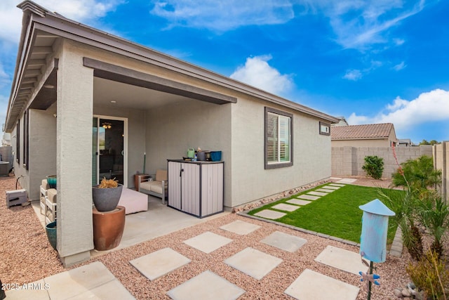 rear view of property featuring stucco siding, a patio, and fence
