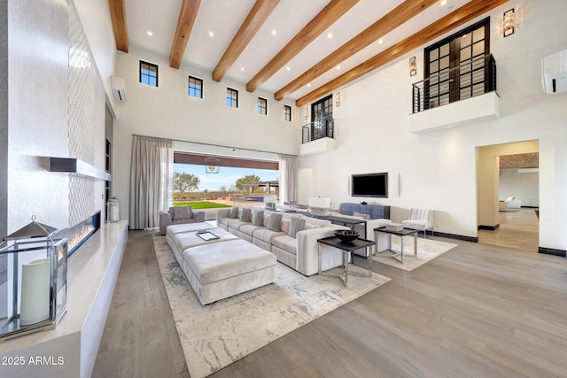 living room featuring beam ceiling, a towering ceiling, and light hardwood / wood-style flooring