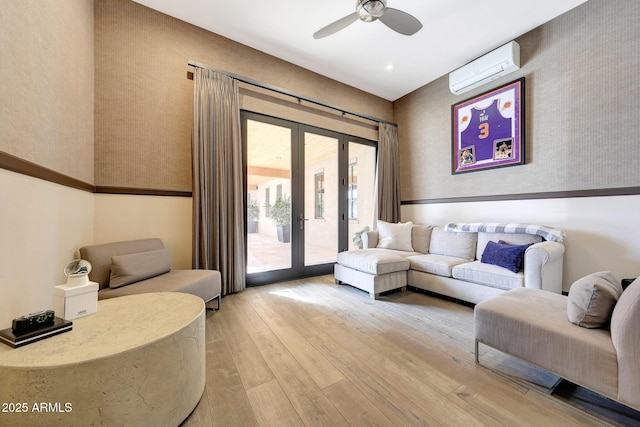 living room featuring a wall mounted air conditioner, ceiling fan, light wood-type flooring, and french doors