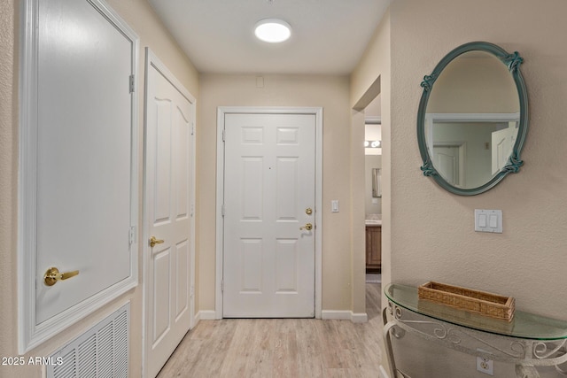 doorway to outside with light wood-style floors, baseboards, and visible vents