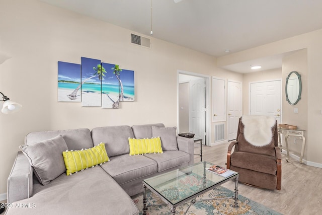living room with baseboards, visible vents, and light wood finished floors