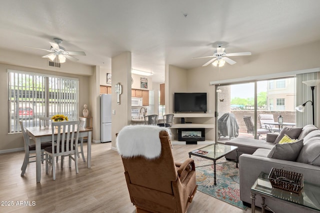 living room with ceiling fan, visible vents, and a wealth of natural light