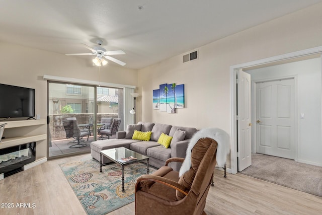 living room featuring light wood-style floors, a ceiling fan, and visible vents