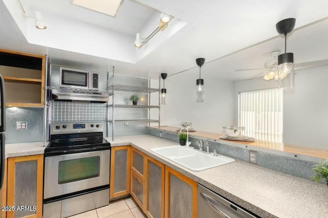 kitchen with sink, light tile patterned floors, a tray ceiling, pendant lighting, and stainless steel appliances