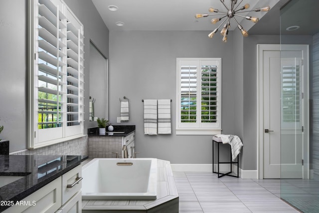 bathroom featuring an inviting chandelier, tile patterned flooring, vanity, and a bathing tub