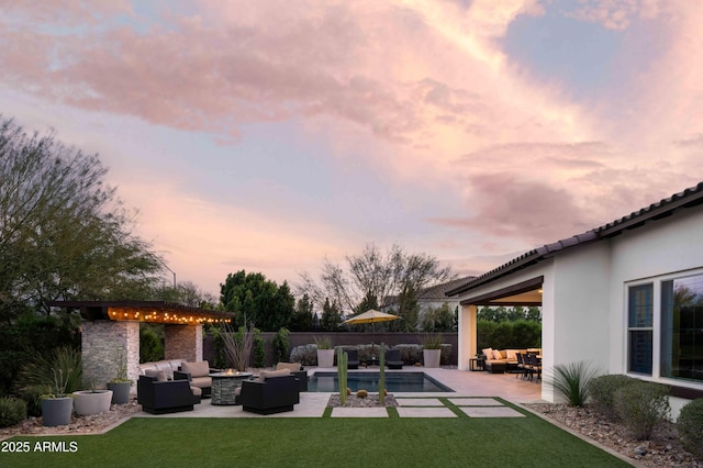 pool at dusk with an outdoor living space, a patio, and a yard