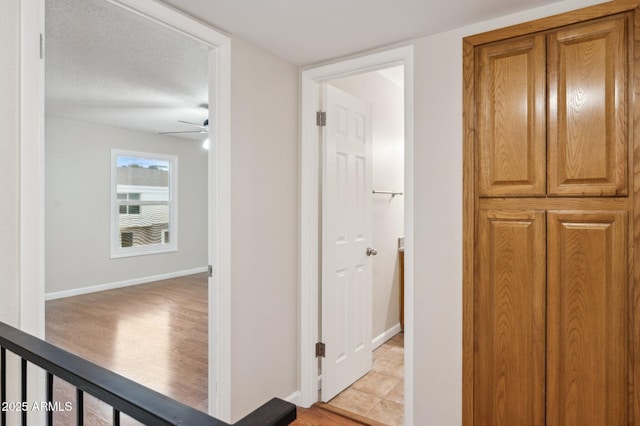 corridor with baseboards and a textured ceiling