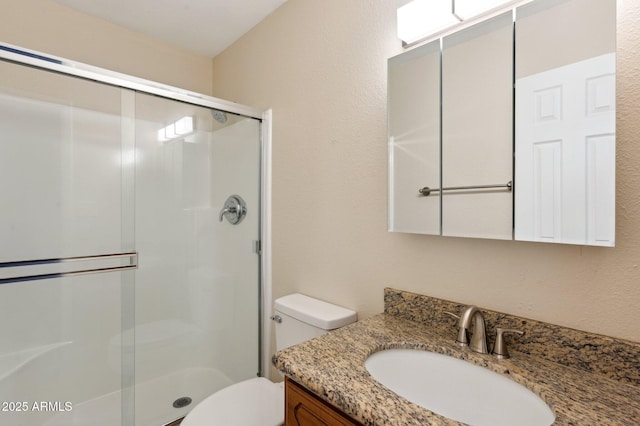 full bath featuring a stall shower, vanity, and toilet