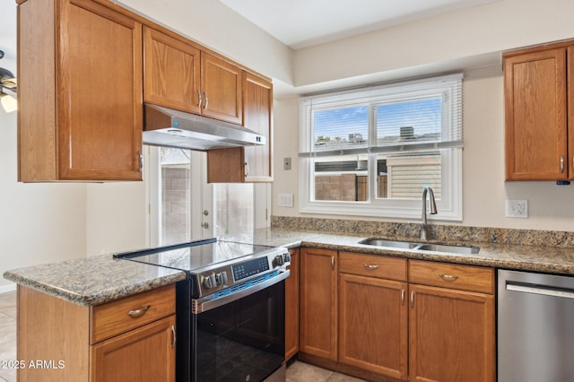 kitchen featuring under cabinet range hood, appliances with stainless steel finishes, brown cabinets, and a sink