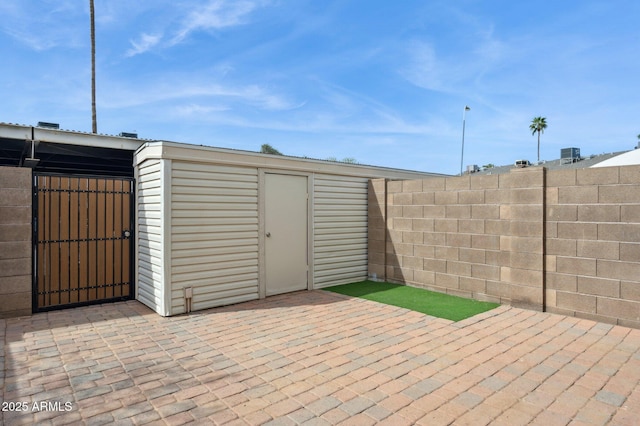 view of outbuilding featuring fence and a gate