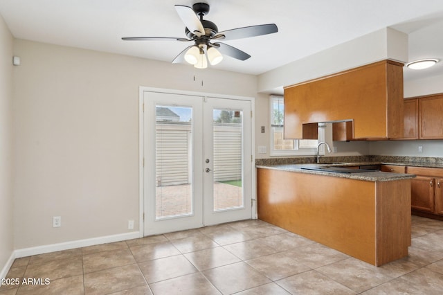 kitchen with light tile patterned floors, a peninsula, french doors, and brown cabinetry