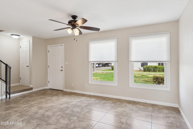 empty room with ceiling fan, stairway, baseboards, and light tile patterned floors