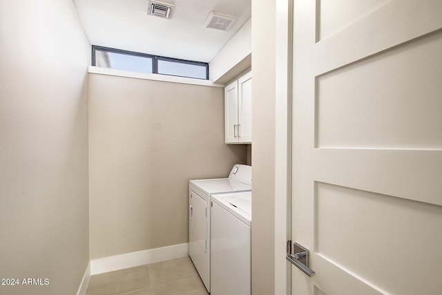 clothes washing area featuring cabinets and washing machine and dryer