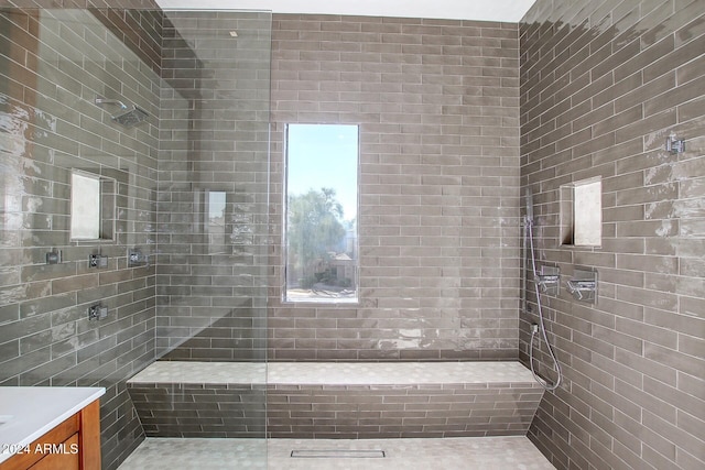 bathroom with a tile shower and vanity