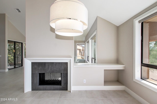 unfurnished living room featuring vaulted ceiling, light tile patterned floors, and a tiled fireplace