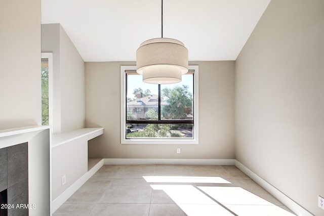 unfurnished dining area with lofted ceiling, a healthy amount of sunlight, and light tile patterned floors