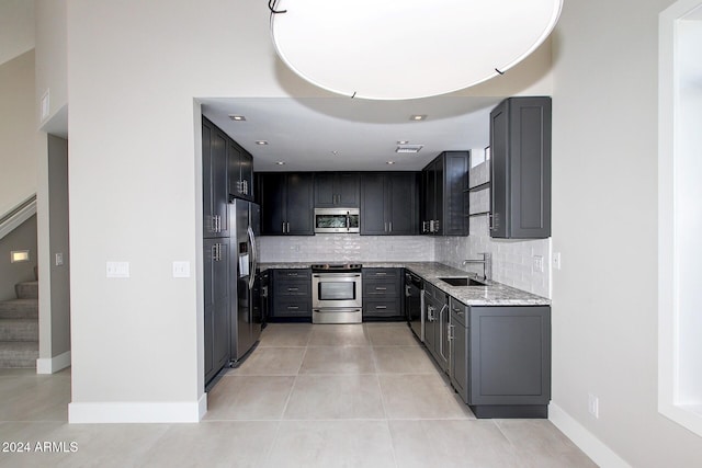 kitchen with light stone countertops, tasteful backsplash, stainless steel appliances, sink, and light tile patterned floors