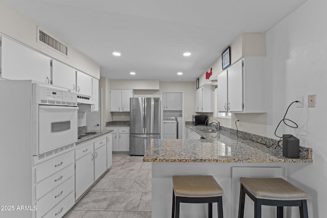 kitchen featuring white cabinetry, stainless steel appliances, a kitchen breakfast bar, and kitchen peninsula