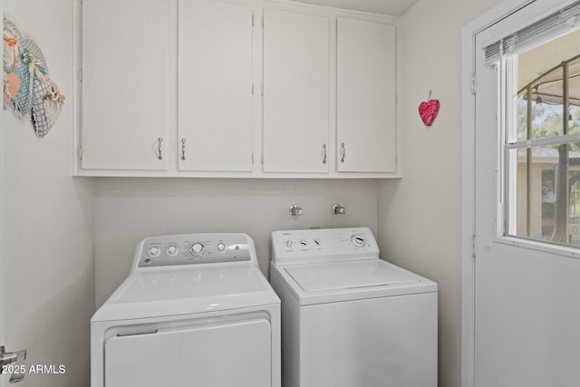 clothes washing area featuring cabinets and independent washer and dryer