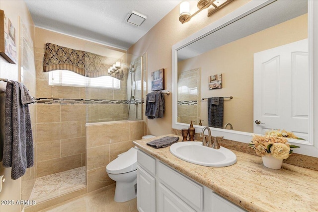 bathroom featuring vanity, toilet, and a tile shower