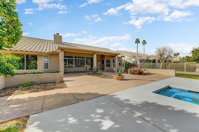 back of property with an in ground hot tub and a patio area