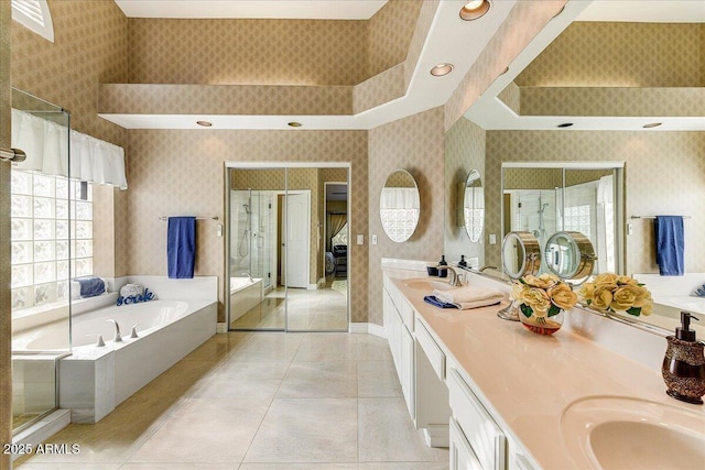 bathroom featuring a towering ceiling, vanity, separate shower and tub, and tile patterned flooring