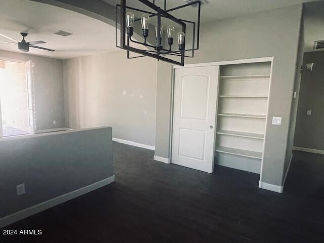 unfurnished dining area featuring ceiling fan with notable chandelier and dark hardwood / wood-style floors