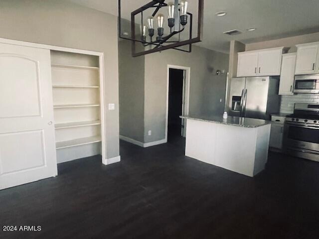 kitchen featuring appliances with stainless steel finishes, white cabinets, backsplash, dark hardwood / wood-style floors, and a chandelier