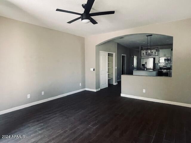 unfurnished living room featuring ceiling fan and dark hardwood / wood-style flooring