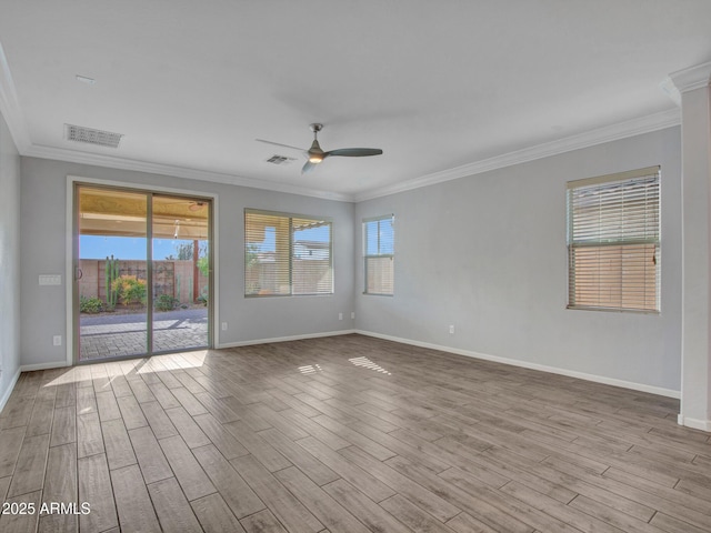 spare room featuring crown molding, visible vents, a ceiling fan, wood finished floors, and baseboards