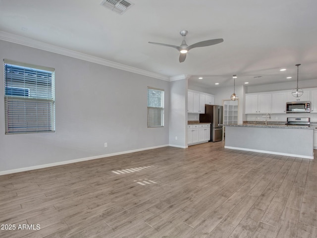 unfurnished living room featuring a ceiling fan, visible vents, baseboards, ornamental molding, and light wood-type flooring