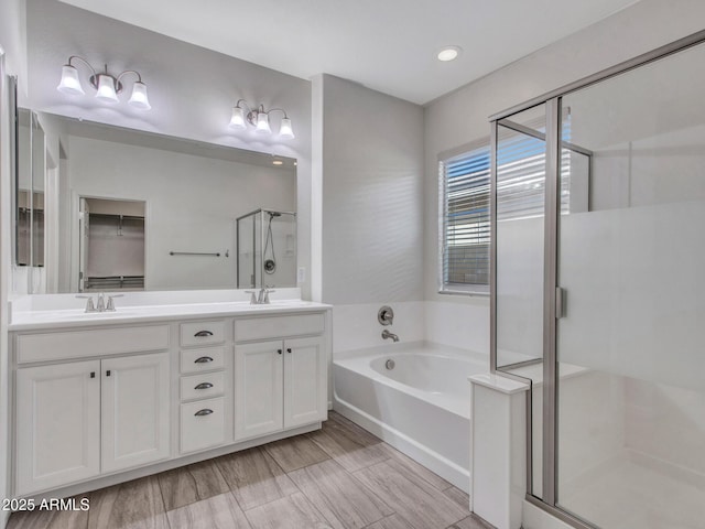 bathroom with a stall shower, double vanity, a sink, and a bath