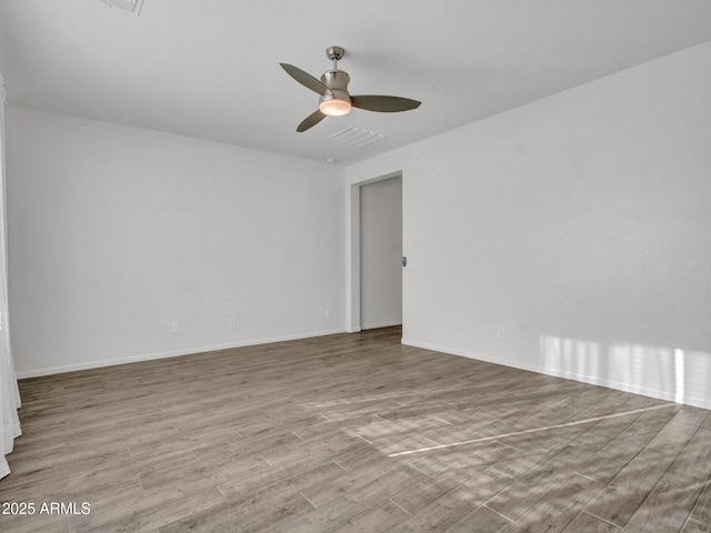 unfurnished room with ceiling fan, wood finished floors, visible vents, and baseboards