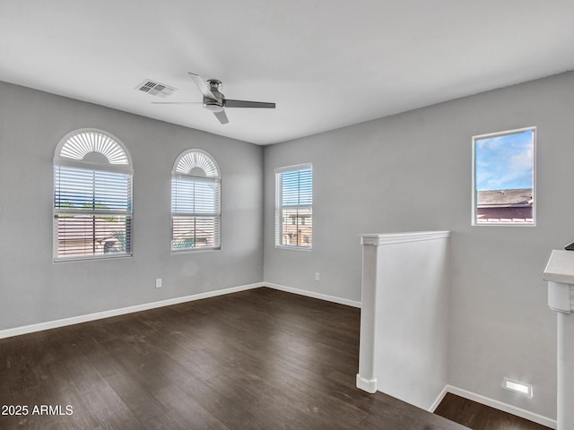 spare room featuring a ceiling fan, visible vents, baseboards, and wood finished floors