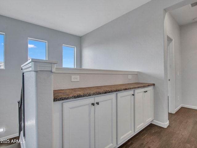 kitchen featuring dark wood-type flooring, white cabinets, visible vents, and baseboards