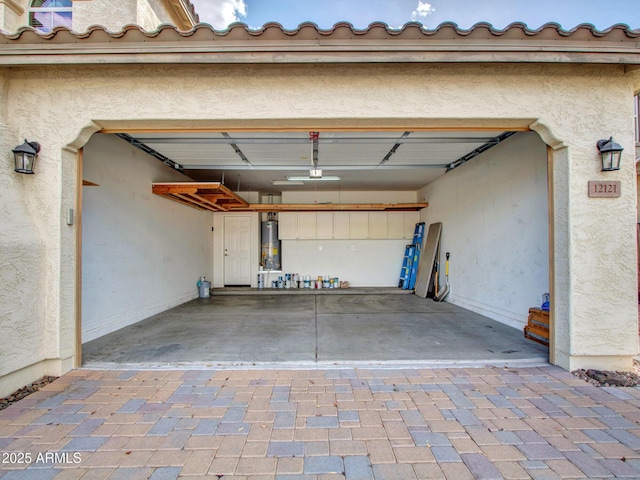 garage with decorative driveway and gas water heater