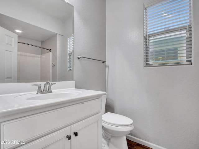 bathroom with a textured wall, toilet, vanity, wood finished floors, and baseboards