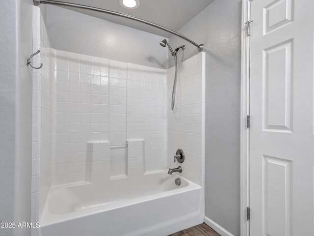 bathroom with shower / bath combination, wood finished floors, and baseboards