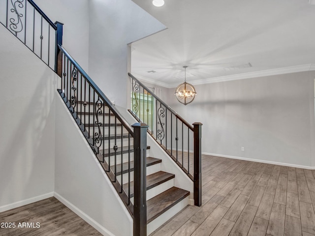 staircase featuring a notable chandelier, baseboards, ornamental molding, and wood finished floors