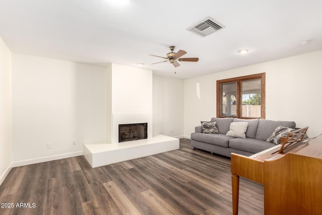 unfurnished living room featuring baseboards, wood finished floors, visible vents, and a fireplace with raised hearth