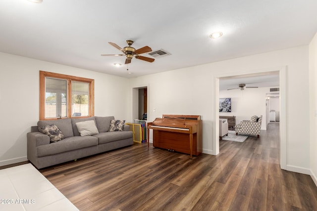 living area with visible vents, baseboards, dark wood finished floors, and a ceiling fan