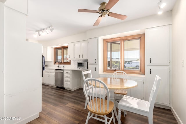 dining space with dark wood finished floors, rail lighting, baseboards, and ceiling fan