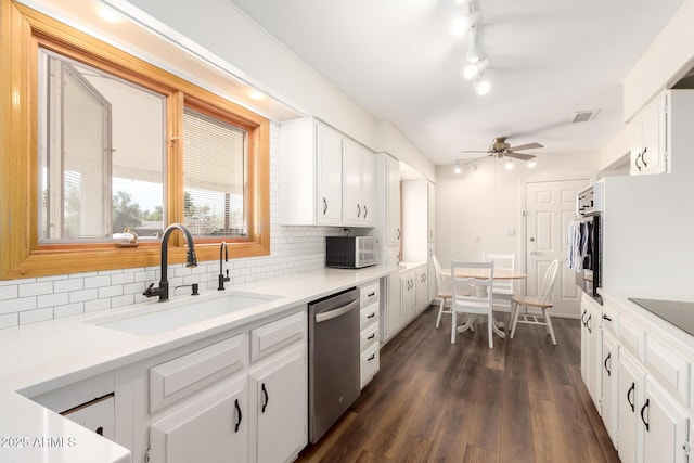 kitchen with white cabinetry, dark wood finished floors, a sink, dishwasher, and tasteful backsplash