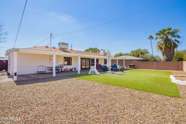 rear view of property with fence, a lawn, and a patio area