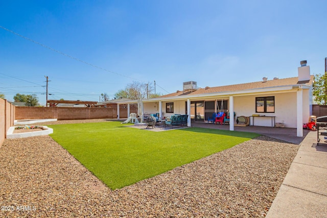 back of property featuring a yard, a patio, a fenced backyard, and a chimney