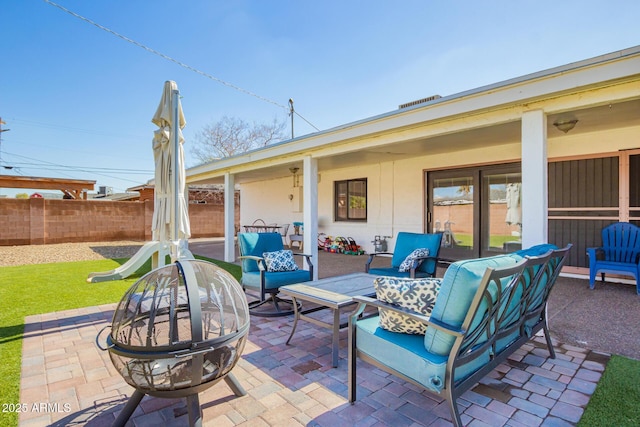 view of patio with an outdoor living space with a fire pit and fence